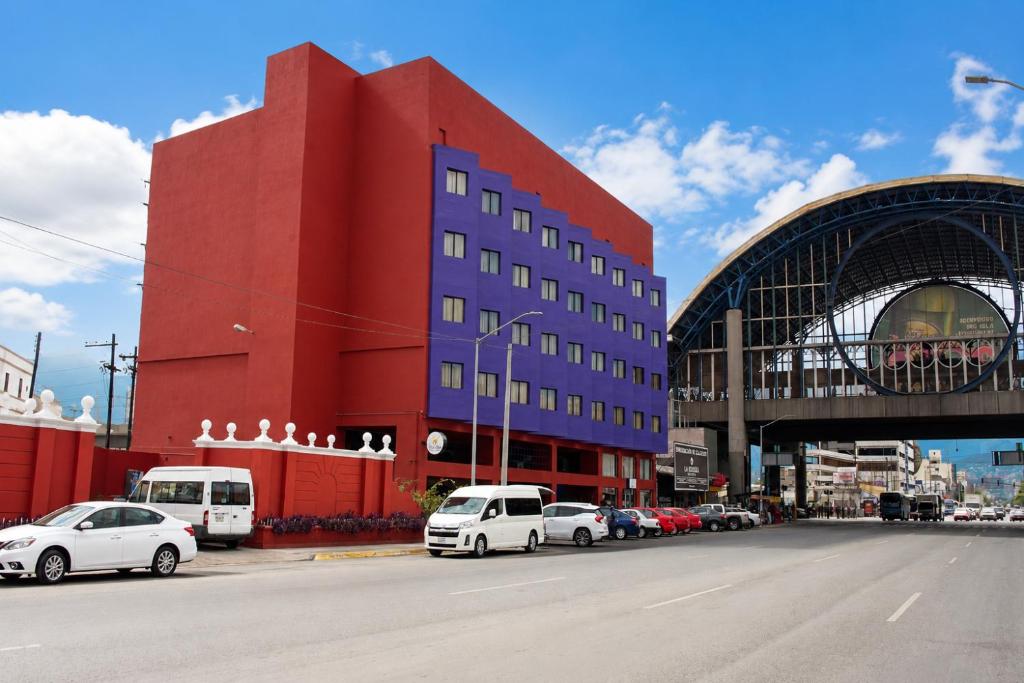 モンテレイにあるHotel Son- Mar Monterrey Centroの道路の前に車が駐車されている赤い建物