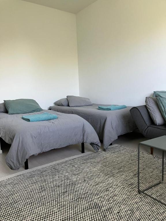 two beds in a room with a couch and a table at Yksiö Koulukadulla - autopaikka - Wi-Fi in Seinäjoki
