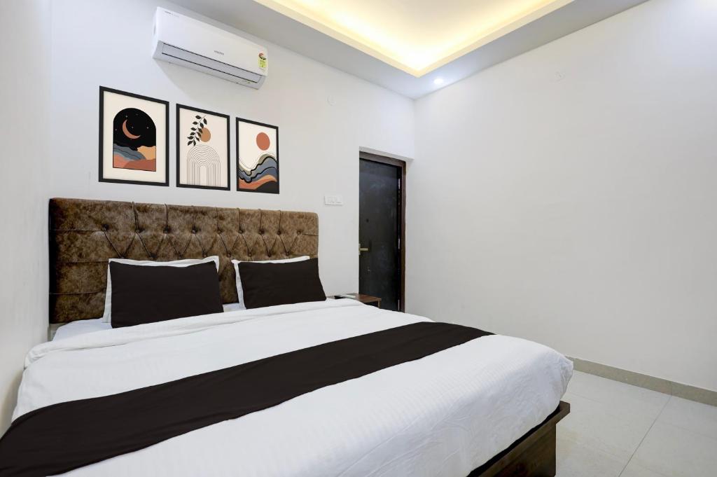 a white bedroom with a large bed and some pictures on the wall at Hotel O White House in Rānchī