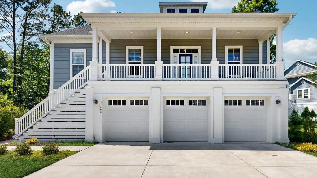a white house with two garage doors at Bethany Woods - 31600 Charleys Run in Bethany Beach