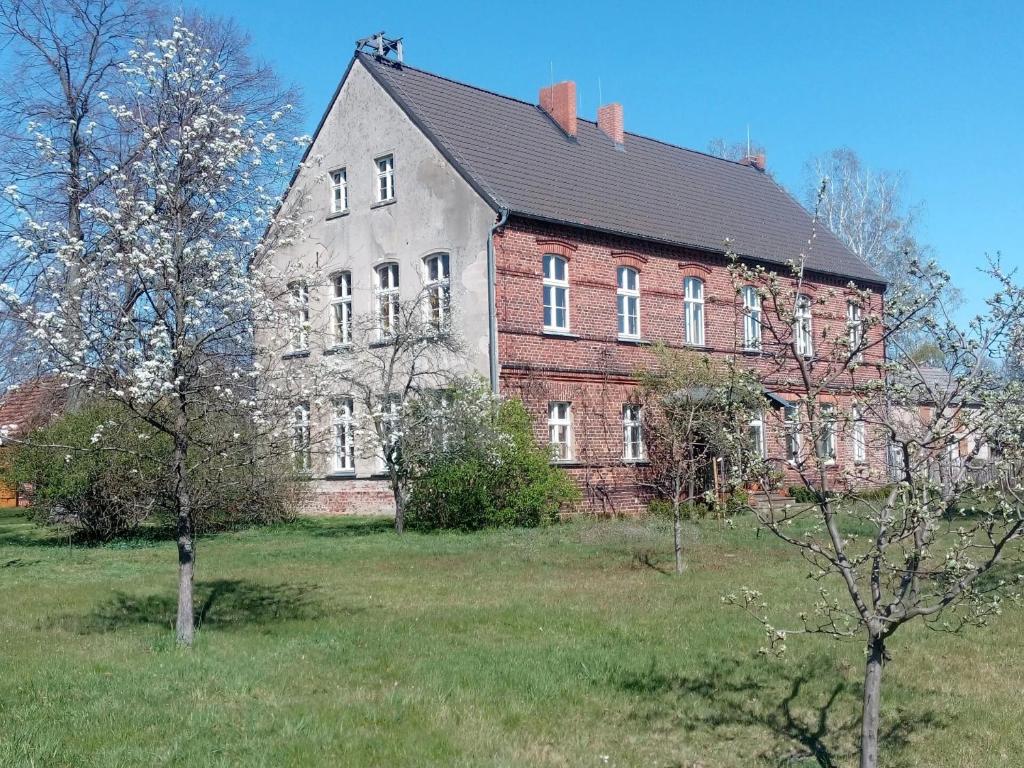 an old brick building in a field with trees at Alte Dorfschule Sacro in Sacro