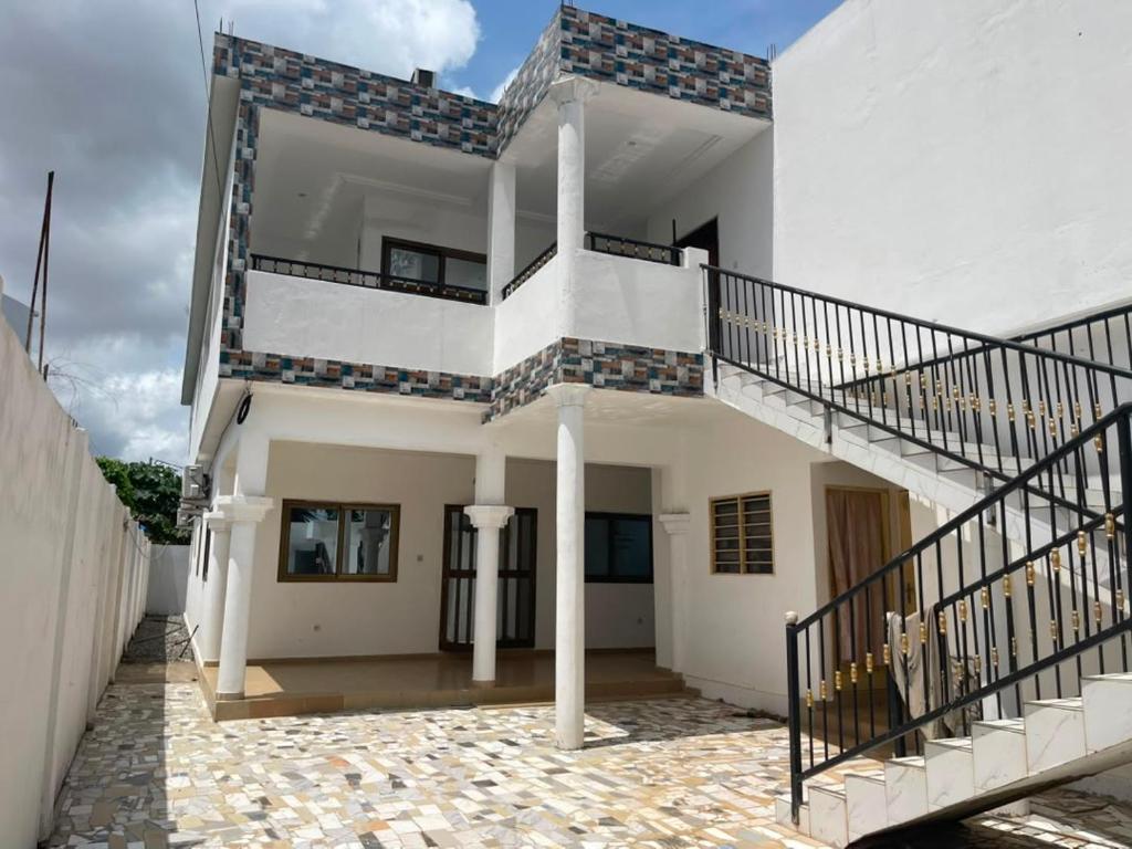 a white house with a staircase and a balcony at RESIDENCE Chez PETER in Alakopé