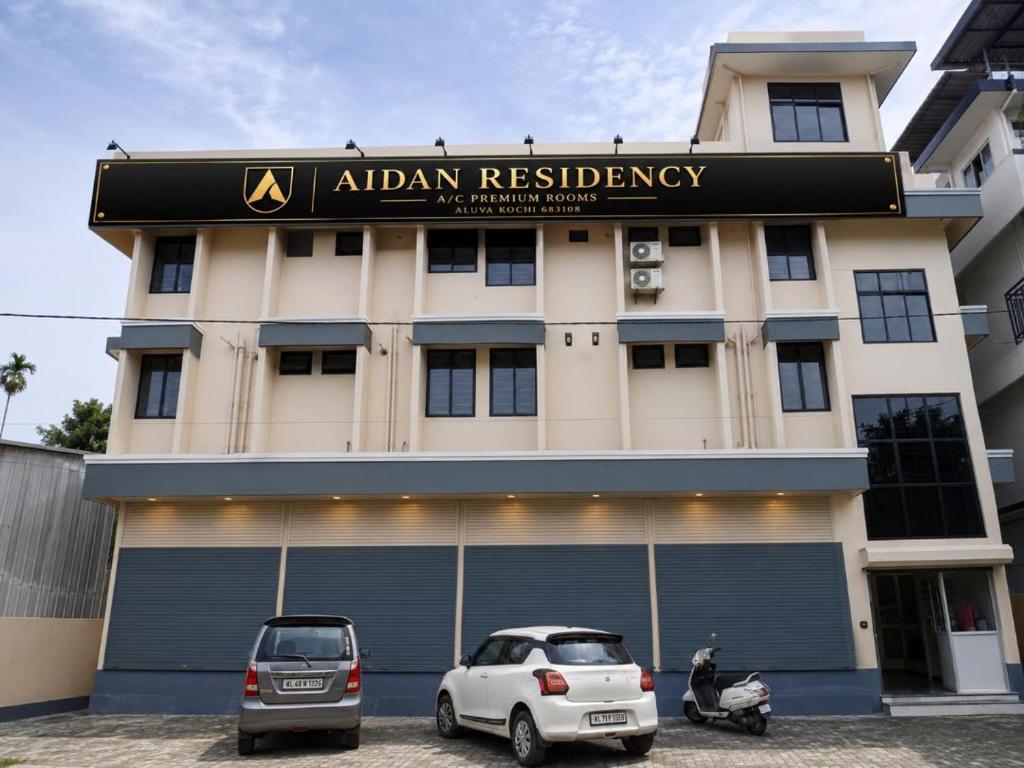 two cars parked in front of a building at AIDAN RESIDENCY - AC Premium Rooms in Alwaye