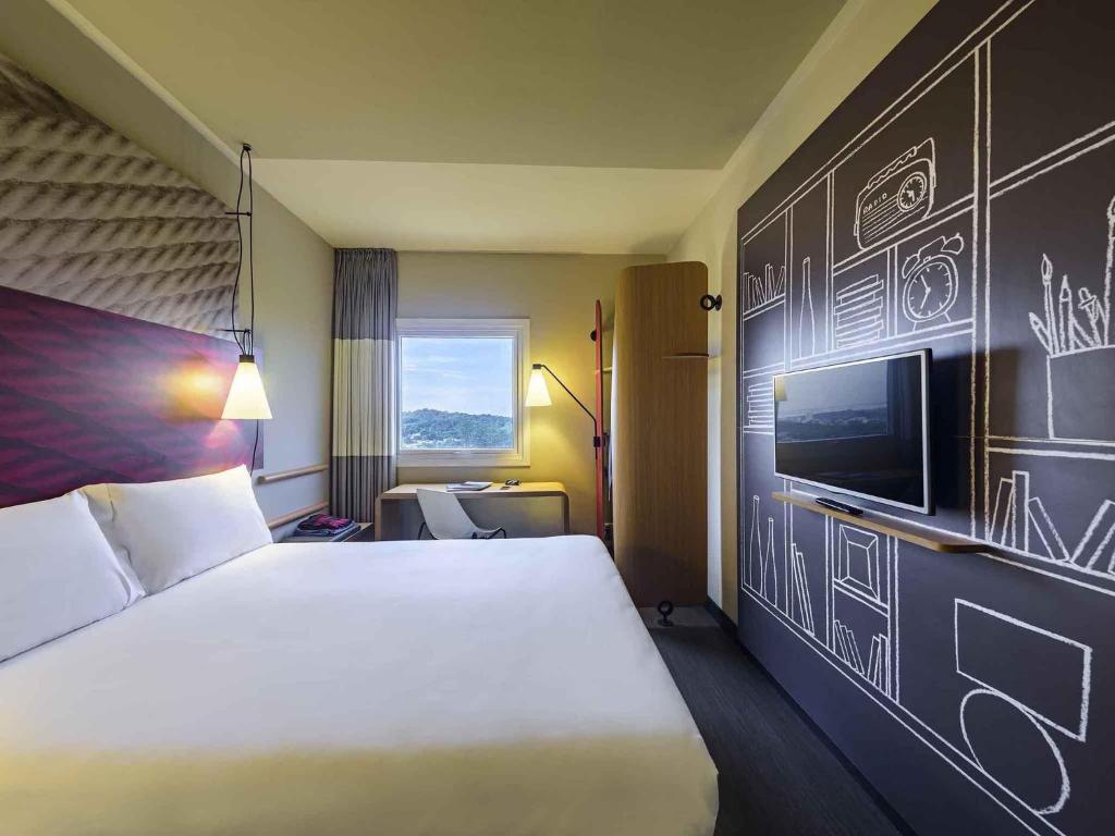 a hotel room with a bed and a tv at ibis Guaiba in Guaíba