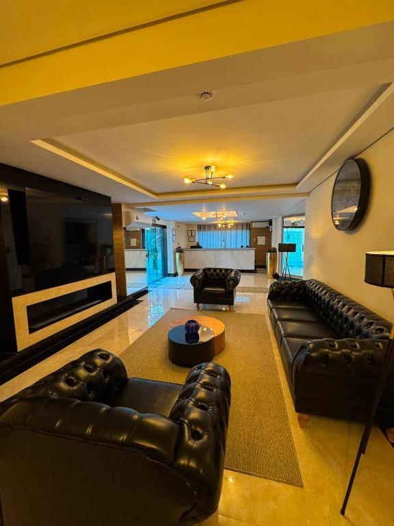 a living room with leather couches and a tv at Le Bonne Ville Hotel in Campos do Jordão