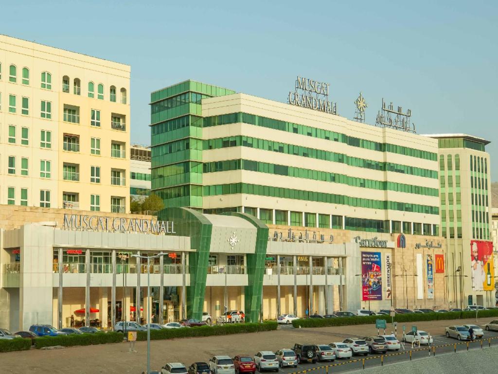 a large building with cars parked in a parking lot at MGM Service Apartment by Savills Oman in Muscat