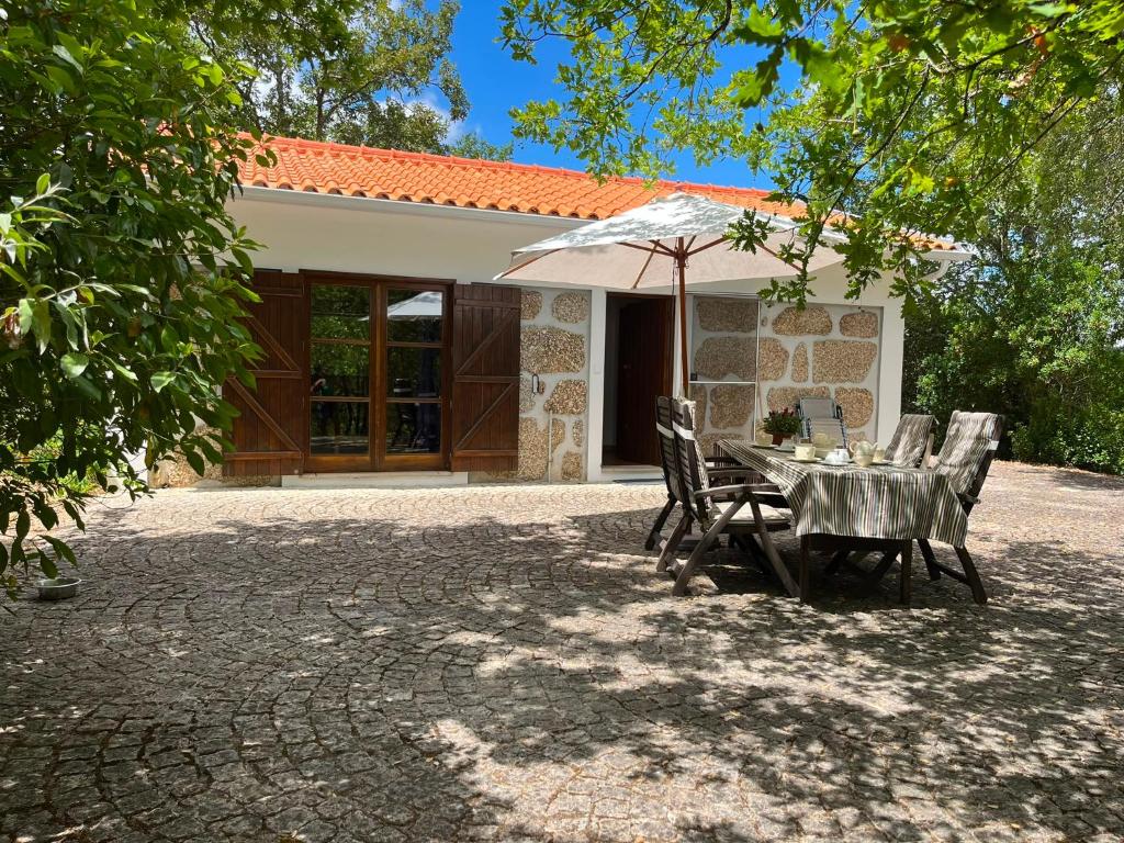 a table and chairs with an umbrella in front of a house at Quinta dos Lagares in Espadanal