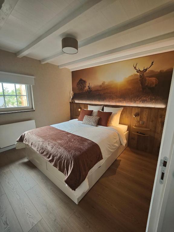 a bedroom with a bed with a painting on the wall at La Brise des Fagnes in Jalhay