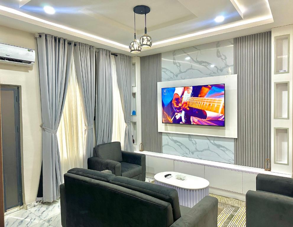 Ein Zimmer mit zwei Stühlen und einem Fernseher an der Wand in der Unterkunft Opic Shortlets in Agege