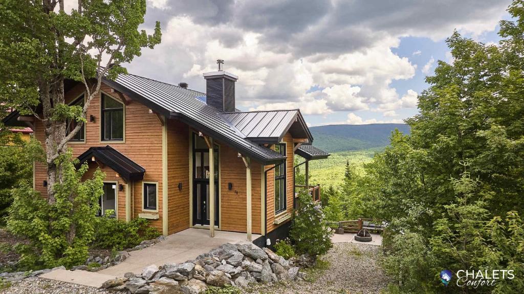 a wooden house with a gambrel roof at Chalet Pourquoi Pas in Saint-Philémon