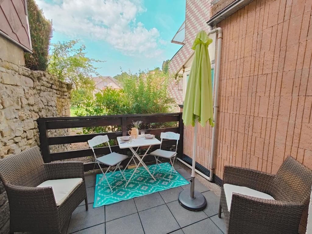 a patio with a table and an umbrella and chairs at Meublé des Capucins - Cocon & Terrasse Privée in Plombières-les-Bains