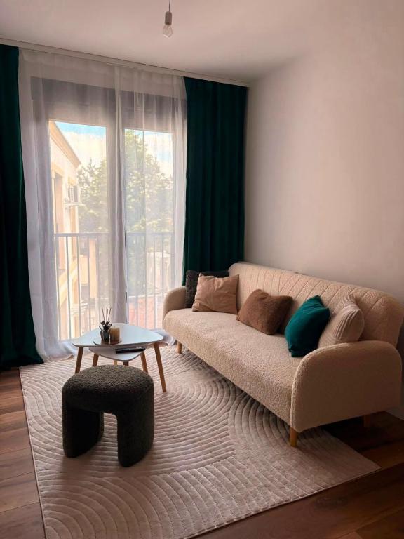 a living room with a couch and a large window at Salt Square Residence in Tuzla
