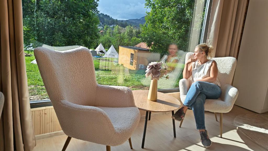 two people sitting in chairs in a window at Pura Vida Mountain Glamping-tiny houses and tents in Moieciu de Jos