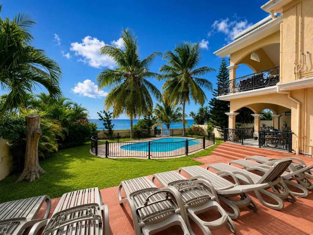 a row of lounge chairs on a patio with a swimming pool at Ocean view in Pointe aux Biches