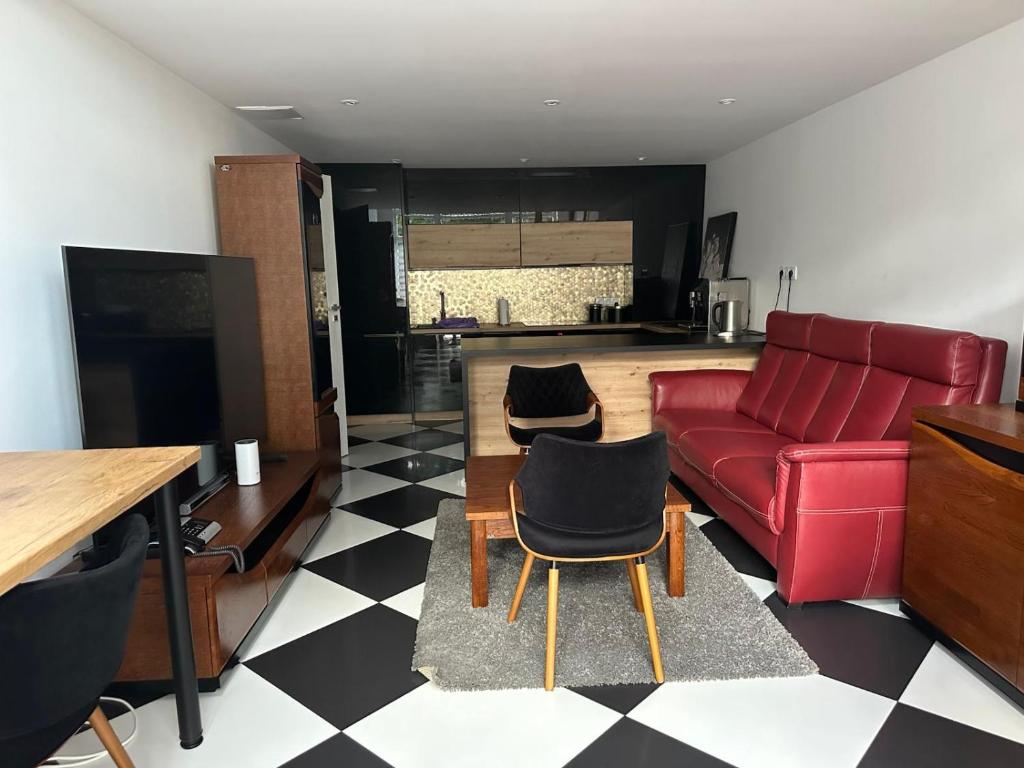 a living room with a red couch and a kitchen at Kościelnik Park Apartament in Lubań
