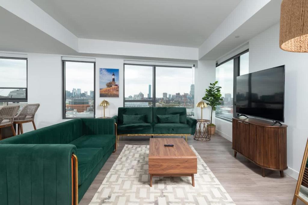 a living room with a green couch and a tv at Central Upscale 2BR Condo wGym Office & Parking in Cambridge