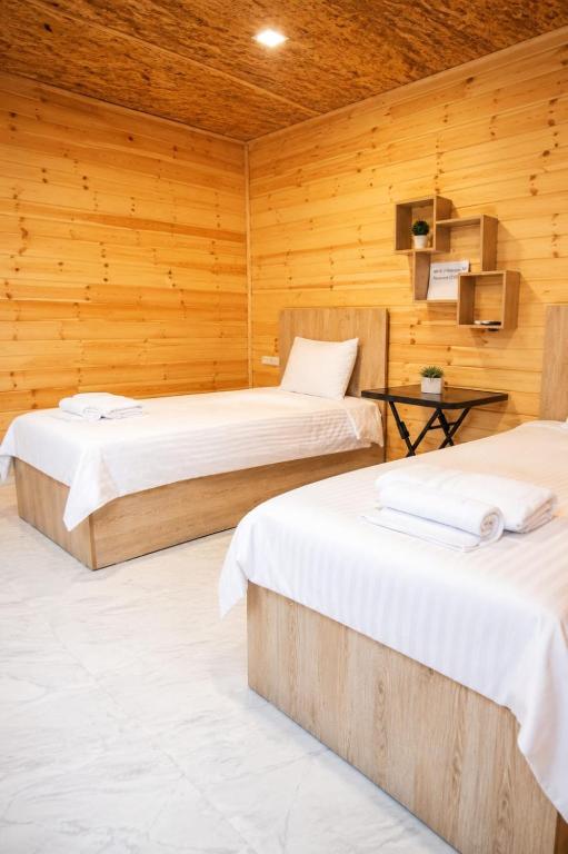 two beds in a room with wooden walls at SkyGate Hotel in Pʼarakʼar