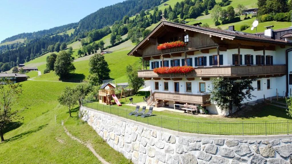 a house on a hill next to a stone wall at Franbichl in Brixen im Thale