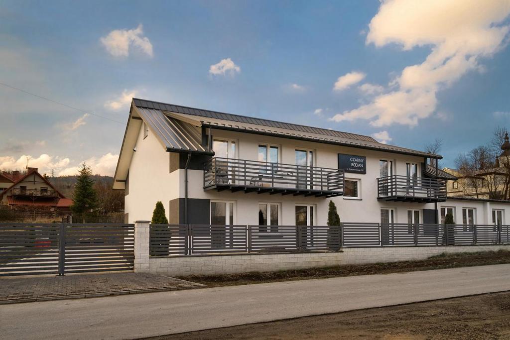a white house with a fence in front of it at Bocian Apartamenty in Krynica Zdrój