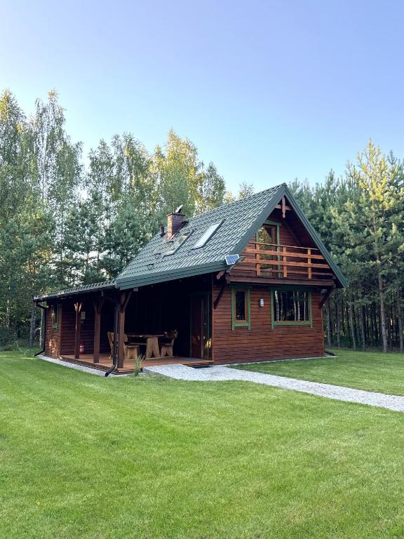a log cabin with a green lawn in front of it at Mazurski lasek in Szwejkowo