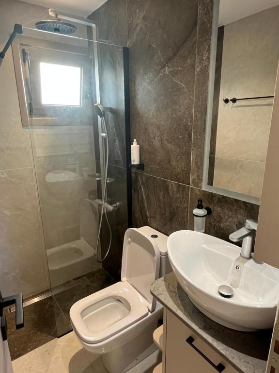 a bathroom with a toilet and a sink and a shower at Latsis Suites in Plytra