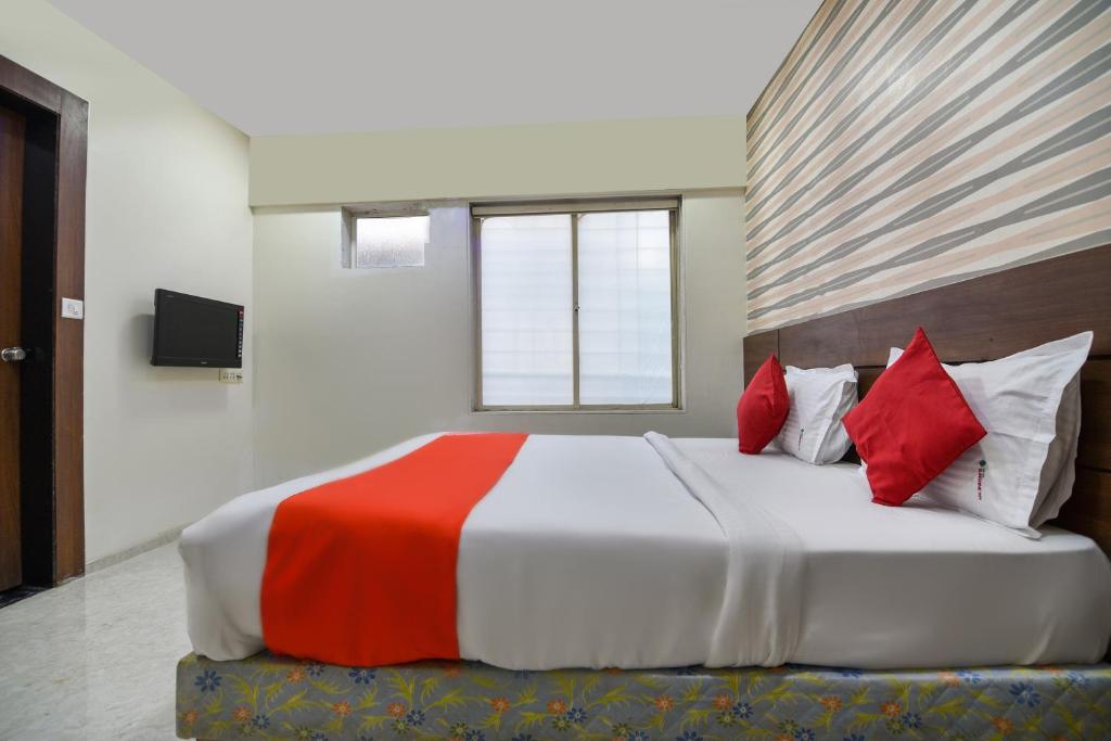 a bedroom with a large bed with red pillows at Hotel O Sunshine Inn Near Pune Railway Station in Pune