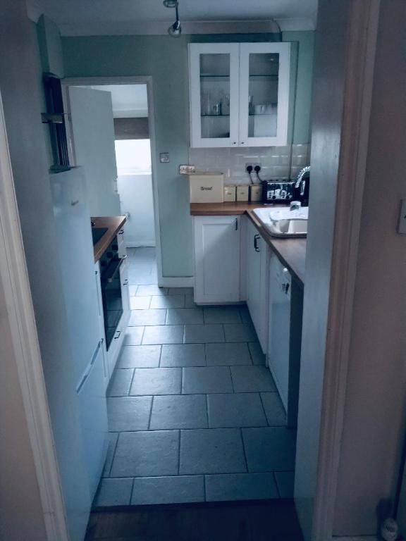 a small kitchen with white cabinets and a tile floor at Sandhurst guest house in Bedford