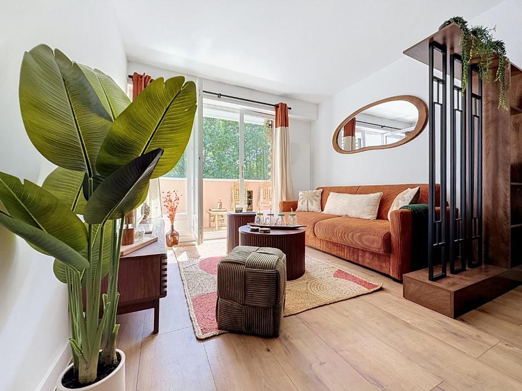 a living room with a couch and a plant at L'Amour des Îles - Centre - Plage - Parking in Cabourg
