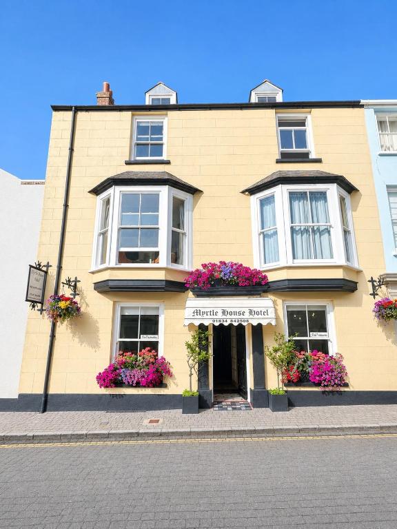 a large yellow building with flowers in front of it at Myrtle House Hotel in Tenby
