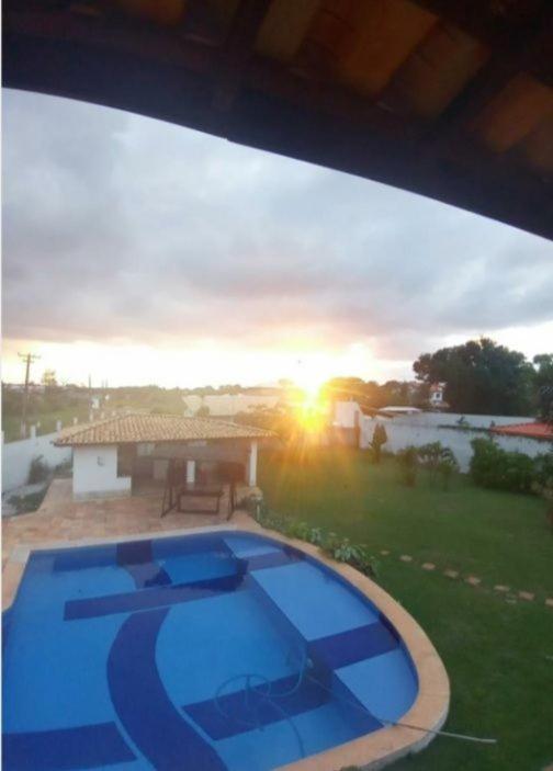 a view of a swimming pool with the sunset in the background at CASA ESTRELA e SOL in Barra de Jacuípe
