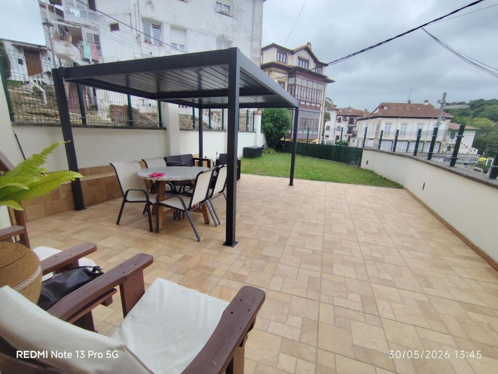 a patio with a table and chairs under a black canopy at Casa Santiago in Comillas