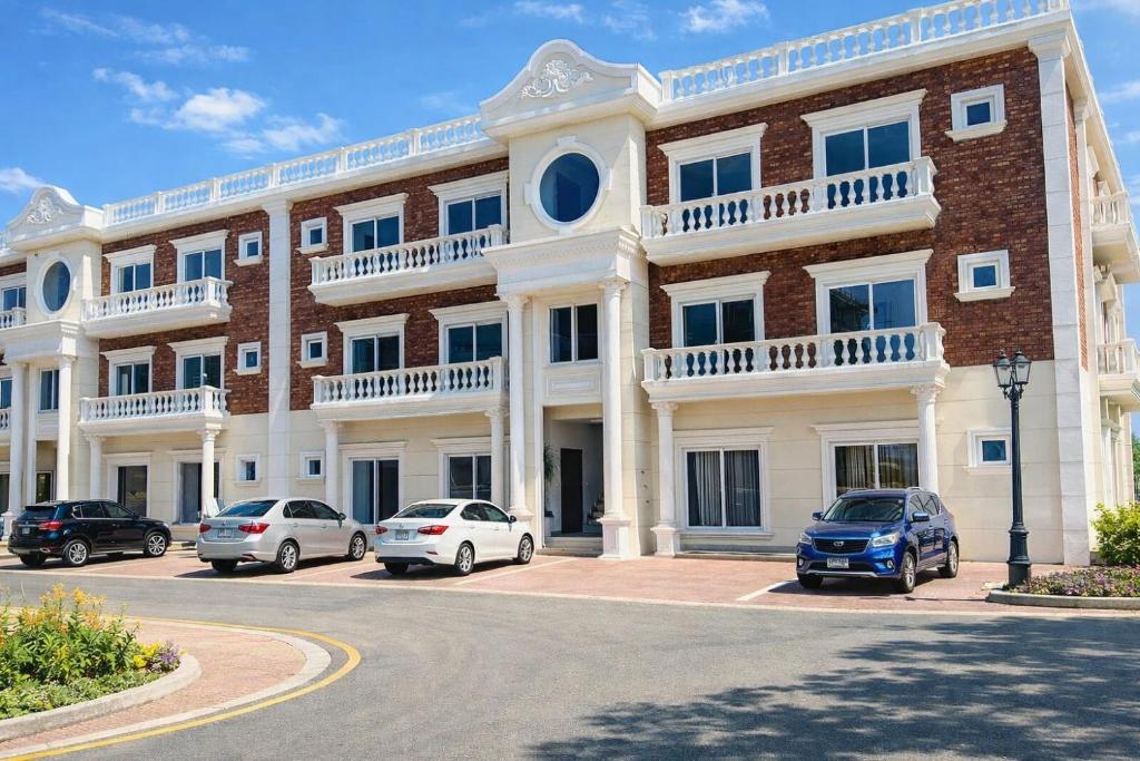 a large brick building with cars parked in a parking lot at Second Stay apartments in Faisalabad
