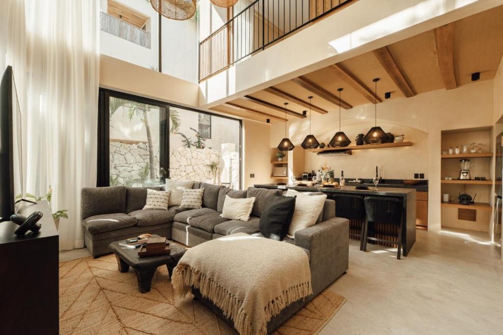 a living room with a couch and a kitchen at Satori Tulum in Tulum