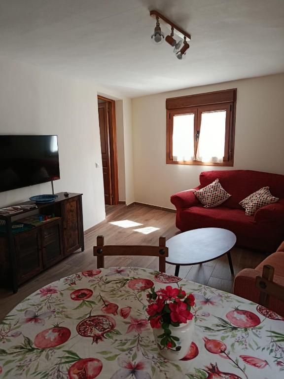a living room with a table and a red couch at La calma de Arnedillo in Arnedillo