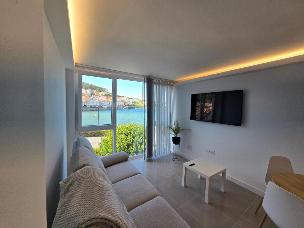 a living room with a couch and a large window at Alborada in Corcubión