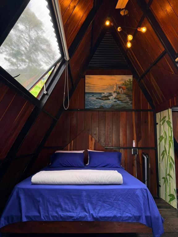 a bed in a wooden room with a window at AJ EcoGlamping in Santo Domingo
