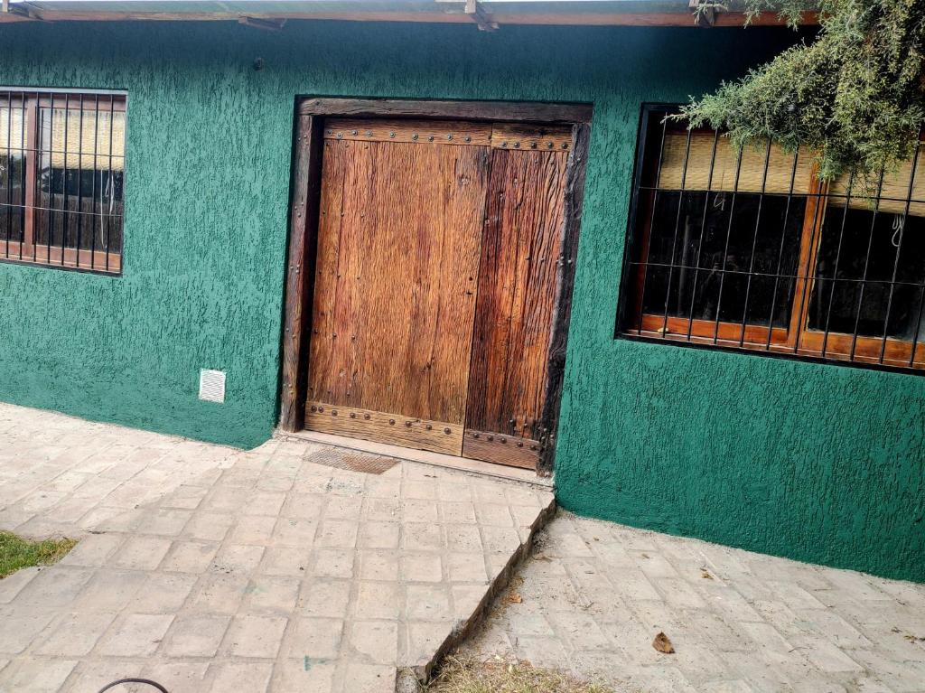 a green building with a wooden door on it at Refugio de Chacras in Ciudad Lujan de Cuyo