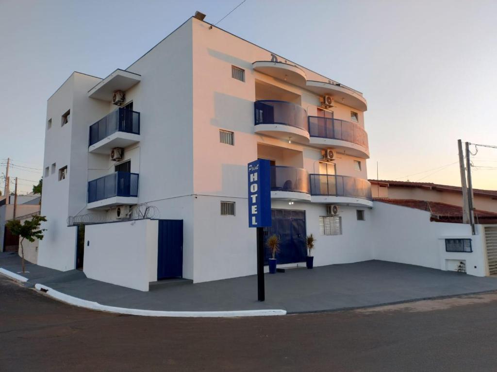 a white building with a blue sign in front of it at Point Hotel in Tanabi