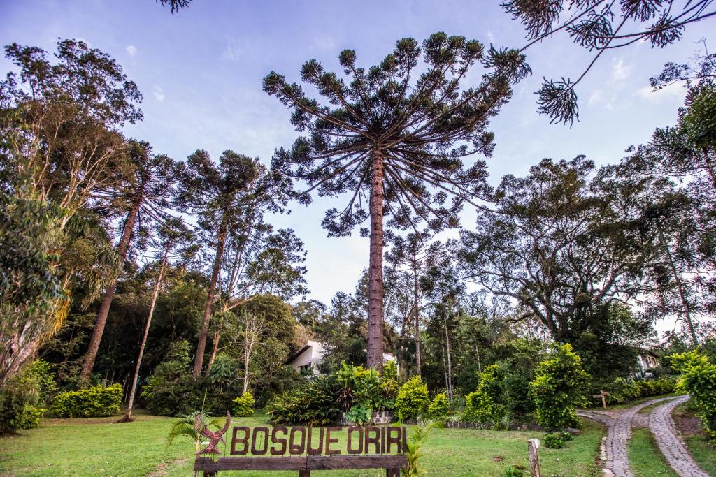 un cartello in un parco con un grande albero di Bosque Oriri a Rebouças