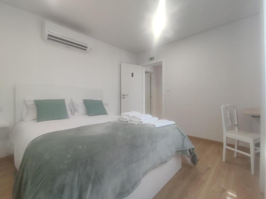 ein weißes Schlafzimmer mit einem Bett und einem Stuhl in der Unterkunft Barcelos Habadia Espigueiro in Lijó