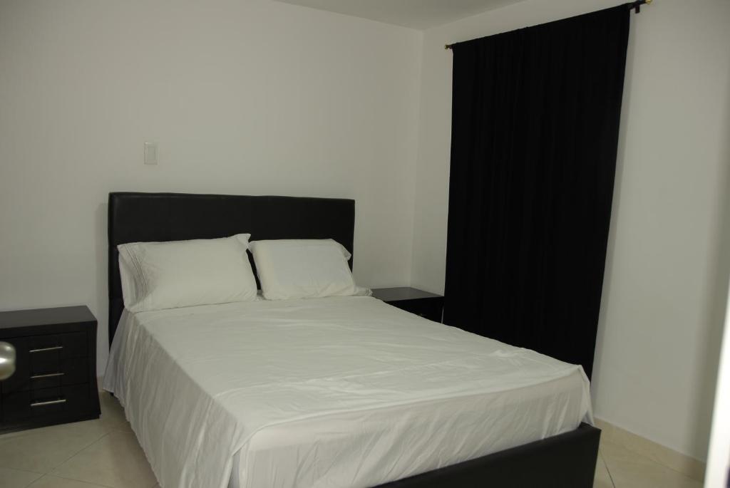 a bedroom with a bed with white sheets and a black headboard at Comfortable Itagüí Stay in Itagüí