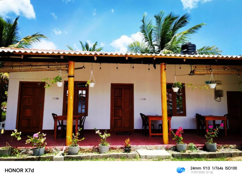 a house with a patio with tables and palm trees at QUEEN SASTINA guest house in Nilaveli