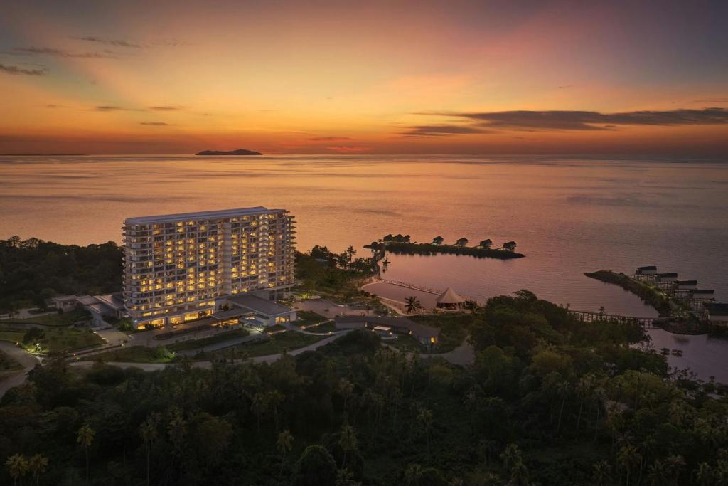 an aerial view of a building on the water at sunset at Manado Marriott Resort & Spa in Manado