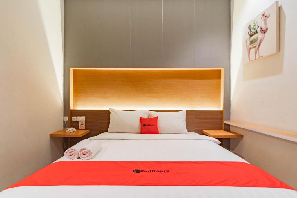 a bedroom with a large bed with a red blanket at RedDoorz Plus @ Doorman Guest House in Bandung