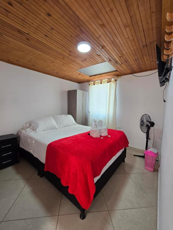 a bedroom with a large bed with a red blanket at Hotel El Balcon de madera in Norcasia
