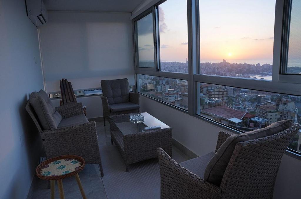 a living room with chairs and a table and windows at Casa Dunia - 2 BR Open Sea View Apartment in Sahl ‘Almā