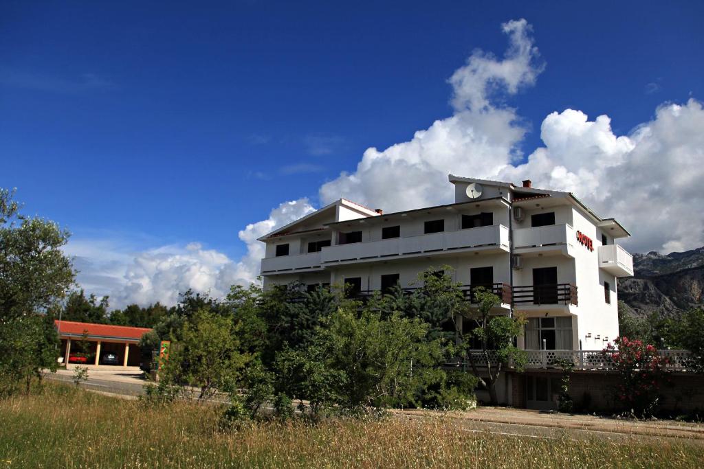 a white building with a mountain in the background at Hotel Rajna in Starigrad