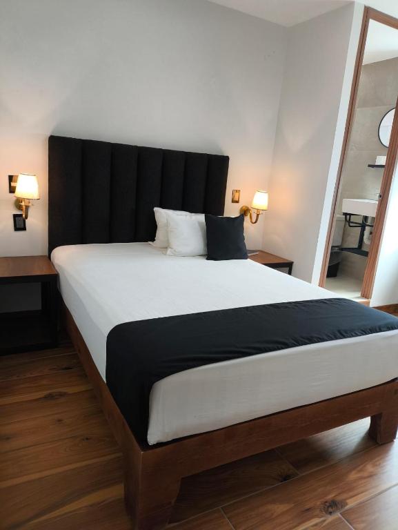 ein Schlafzimmer mit einem großen Bett mit schwarzem Kopfteil in der Unterkunft Hotel Sicilia, Aguascalientes in Aguascalientes
