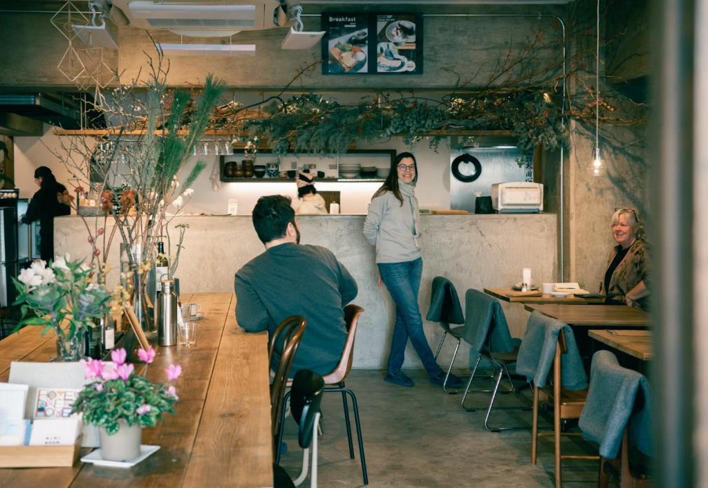 a woman standing behind a counter in a restaurant at Hostel Niniroom in Kyoto