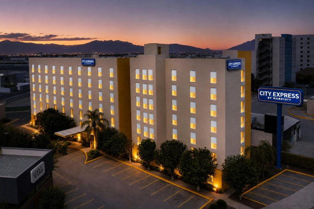 a large white building with a street sign in a parking lot at City Express by Marriott Monterrey Aeropuerto in Monterrey